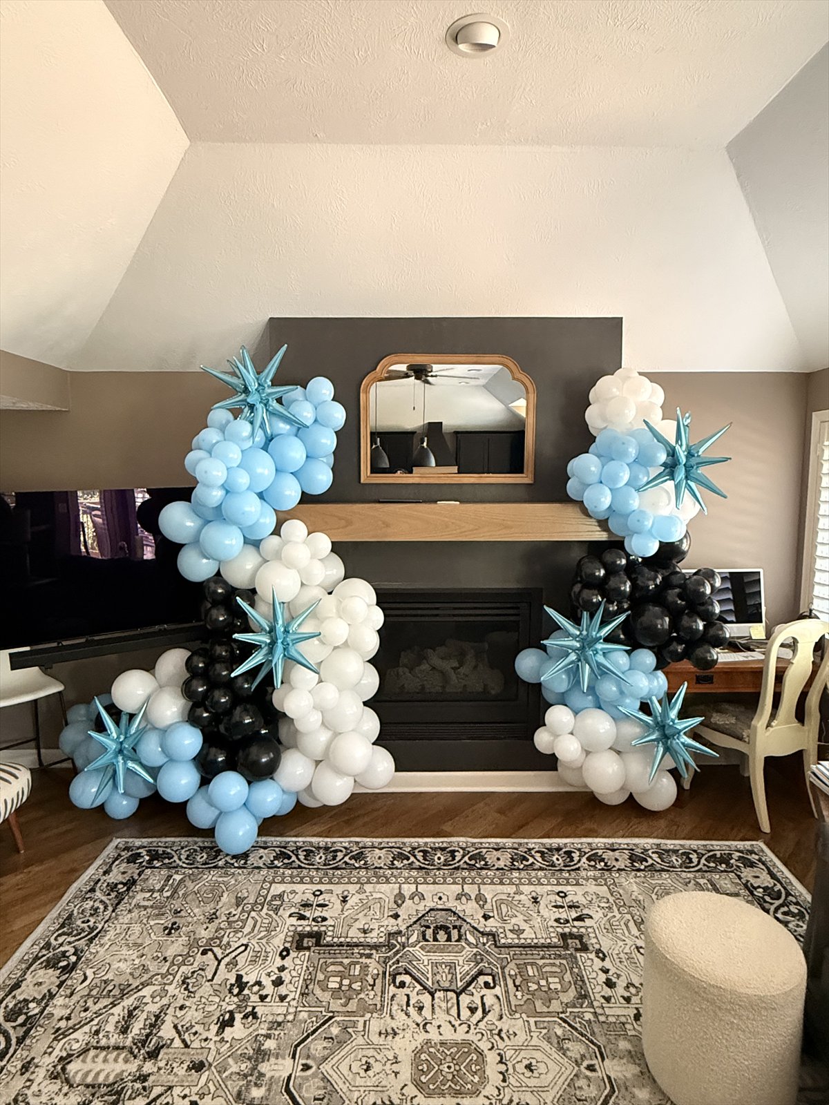 Blue, black, and white balloon installation framing a fireplace