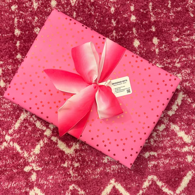 Pink gift wrapped in star-patterned paper and tied with a satin bow