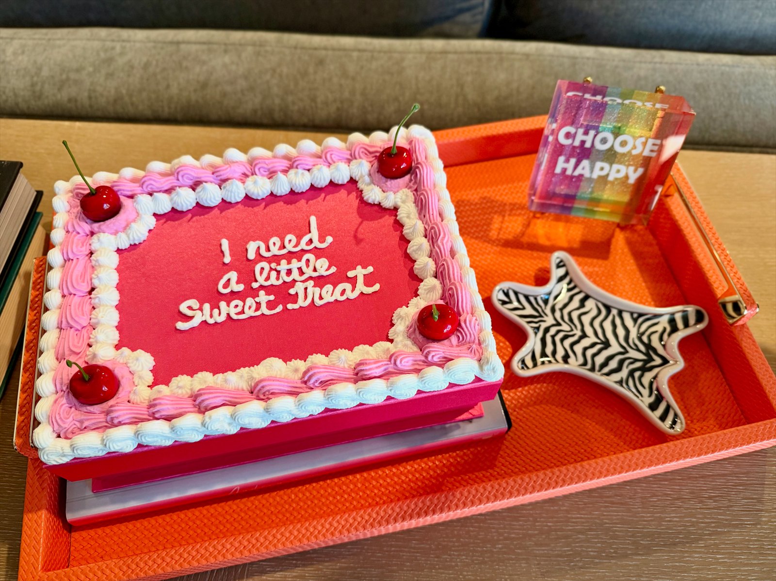Pink sheet cake reading I need a little sweet treat on an orange tray